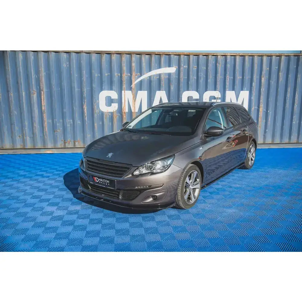 Front lip på Peugeot 308 Mk2 Facelift med sølvfelger, skrå forfra mot blå skipscontainer.