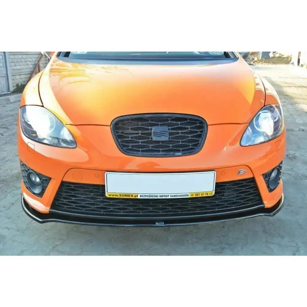 Frontspoiler på oransje Seat Leon Mk2 Cupra med svart frontsplitter og synlig sort emblem.