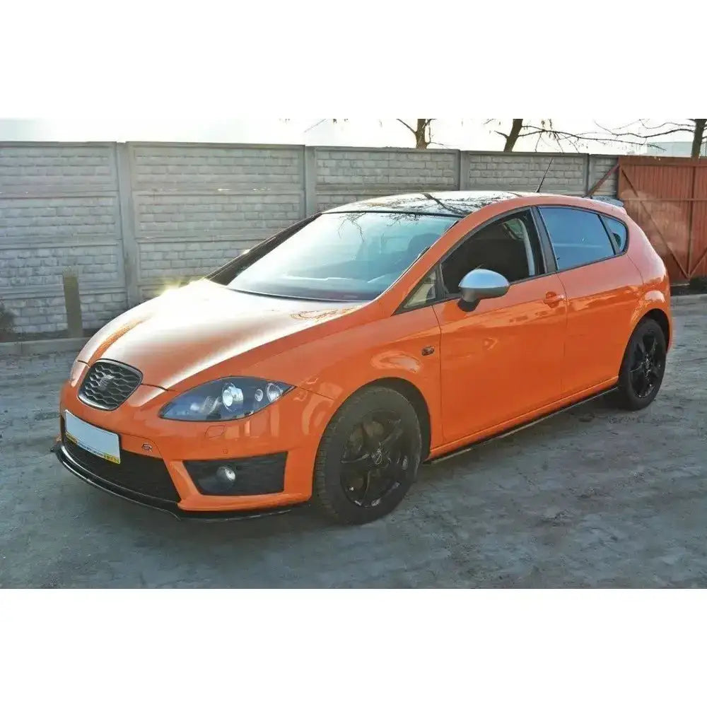 Front lip på oransje Seat Leon Mk2 Cupra med svarte felger og sølvfargede speildeksler, sett skrått forfra.