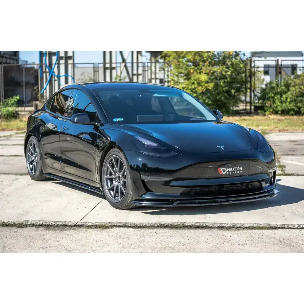 Frontspoiler på svart Tesla Model 3 V.2 sett skrått forfra med blank overflate og sidespoilere.
