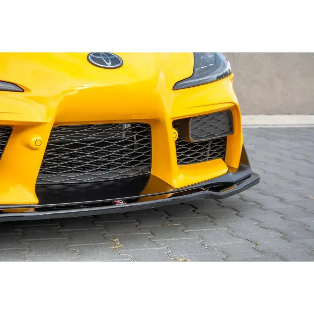 Frontsplitter på gul Toyota Supra Mk5 med sort nettmønstret grill og aerodynamiske detaljer.