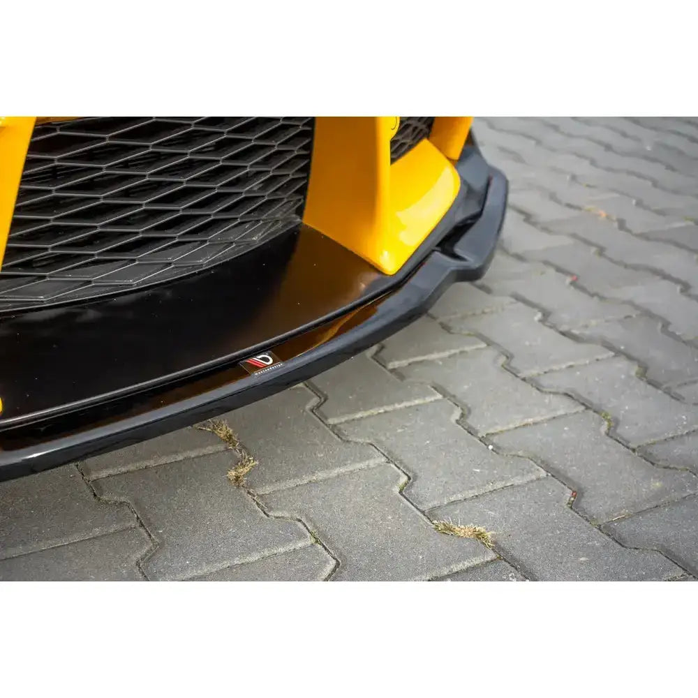 Front splitter påmontert gul Toyota Supra Mk5, nærbilde med blank finish og synlig logo på asfalt.