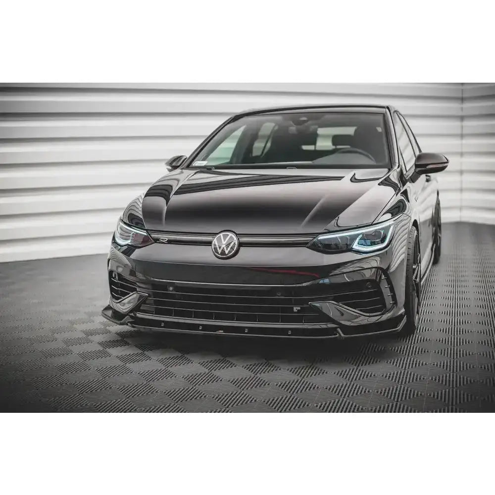 Frontspoiler på Volkswagen Golf R Mk8 V.2, sort bil med sportslig front og LED-lys mot lyse veggpaneler.