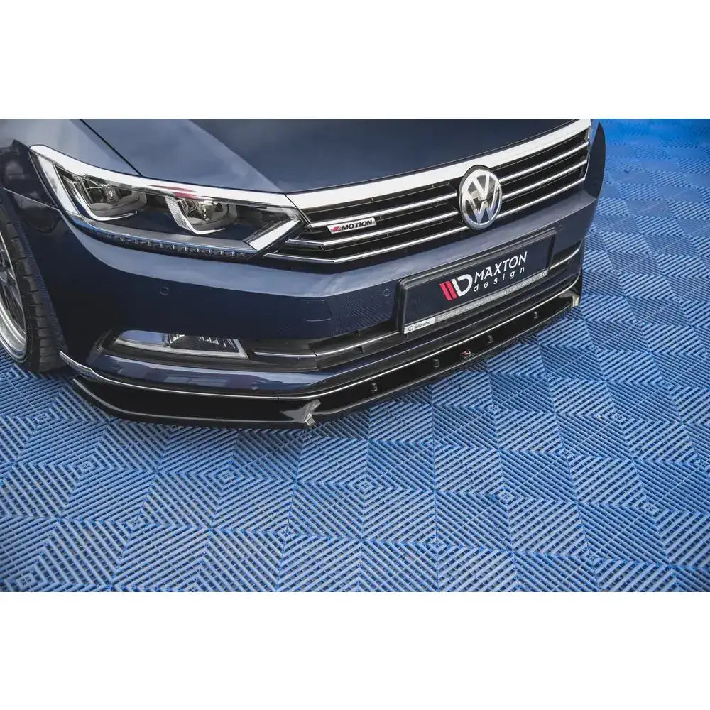 Front lip på Volkswagen Passat B8 med sort, blank frontsplitter, sett skrått forfra over blått gulv.