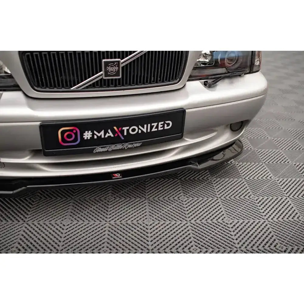 Front lip på Volvo C70 Mk1 med svart, blank frontleppe sett fra lav vinkel mot sølvfarget bil.