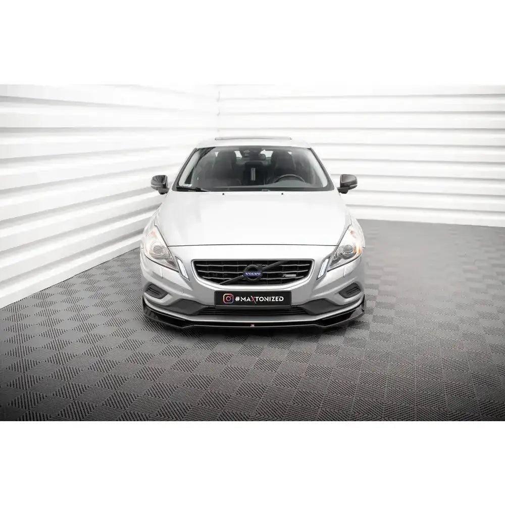 Frontspoiler for Volvo S60 R-Design Mk2, sort modell montert på sølvfarget bil sett forfra.