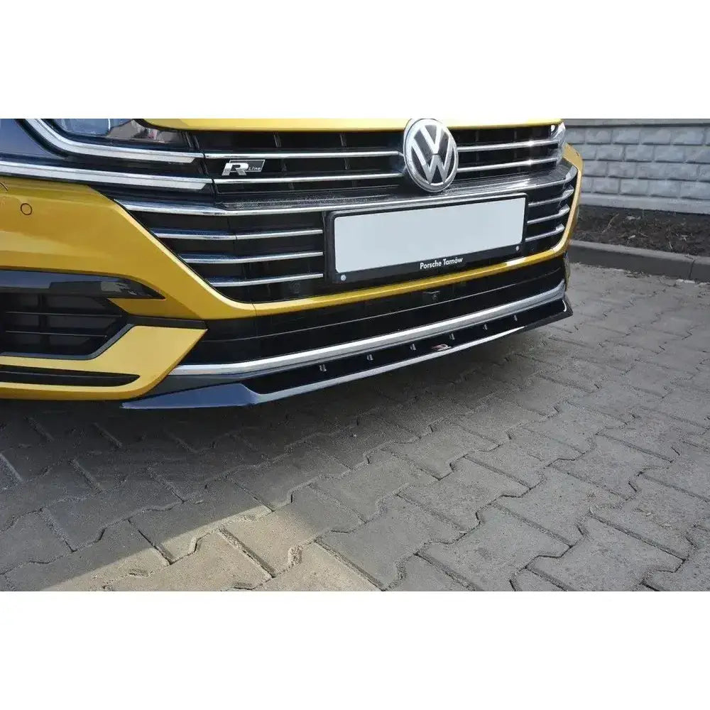Frontspoiler til VW Arteon V.2 montert på gul bil med sort grill og sort frontsplitter utendørs.
