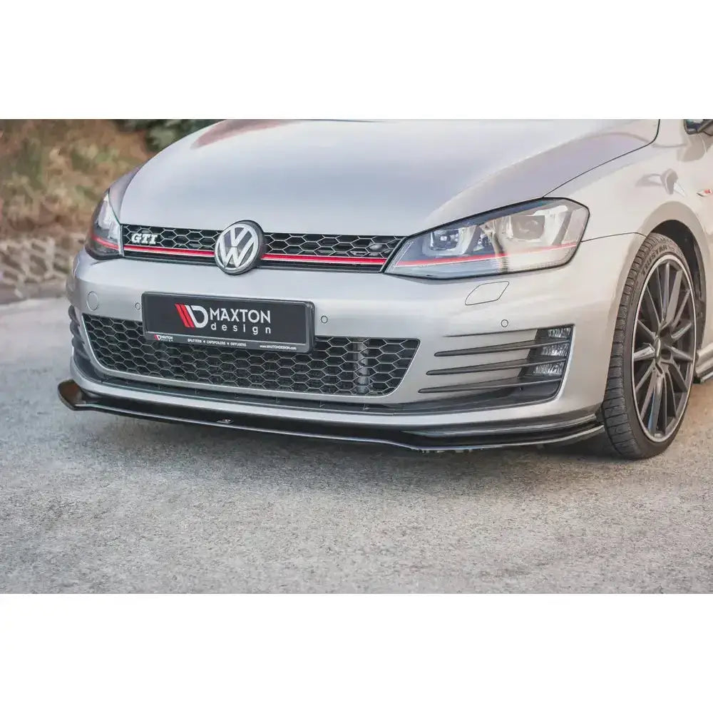 Frontsplitter på sølvfarget VW Golf VII GTI med sorte felger og rød dekorlinje i grillen.