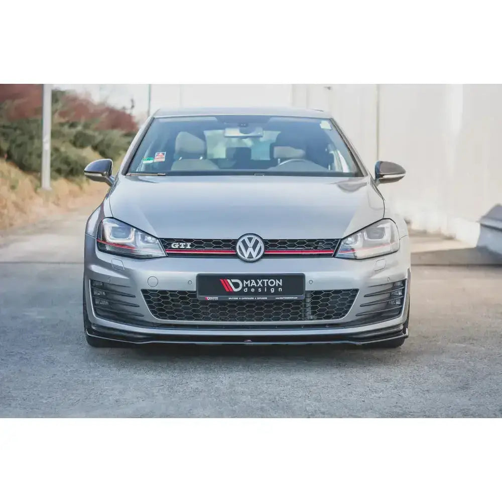 Front splitter på grå VW Golf VII GTI sett forfra med sort frontleppe og rød stripe i grillen.