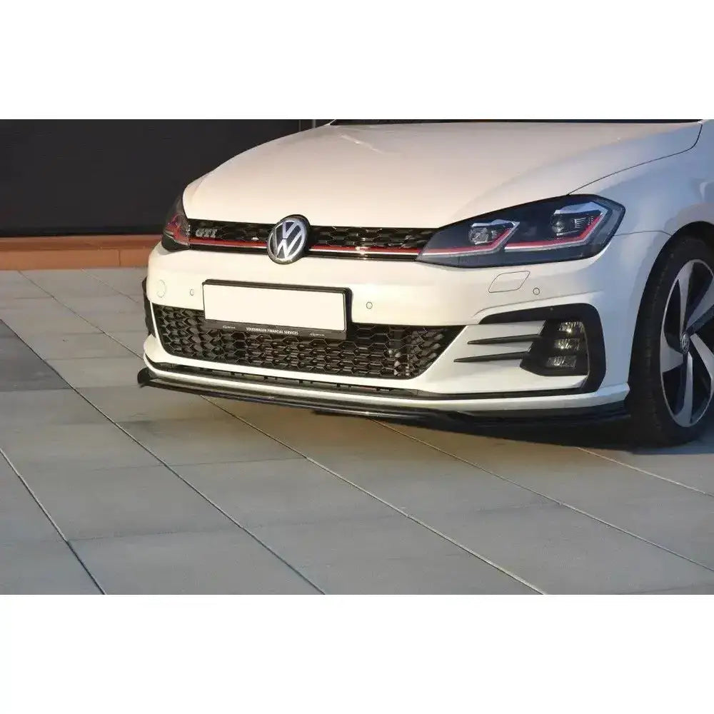 Frontspoiler V.2 til VW Golf VII GTI Facelift montert under støtfanger på hvit bil, sett fra lav vinkel.
