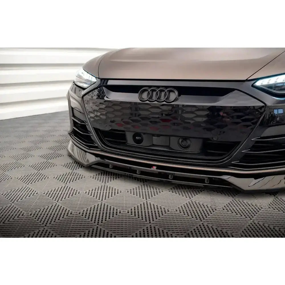 Frontsplitter på sort Audi e-Tron GT Mk1 med synlig grill, logo og frontspoiler, innendørs på mønstret gulv.