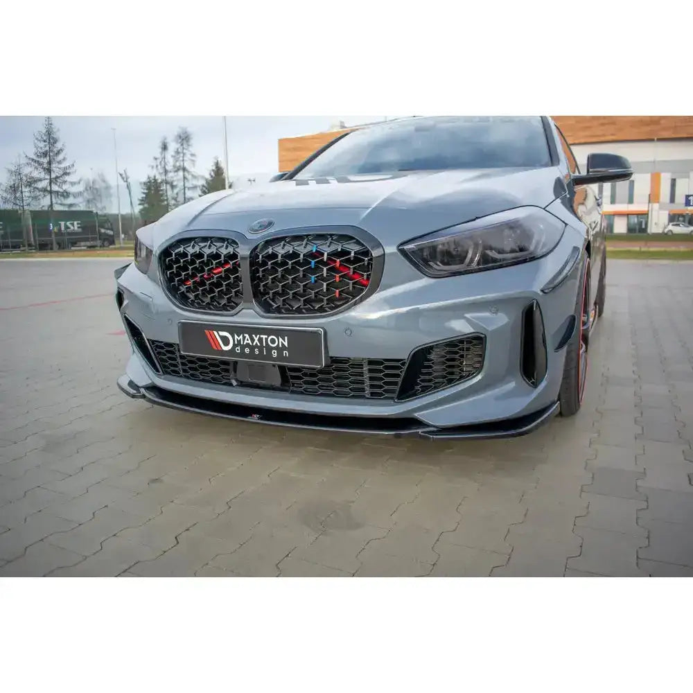 Front lip på BMW 1 F40 M-Pack med sort frontleppe, grill med røde og blå detaljer og Maxton Design-logo.