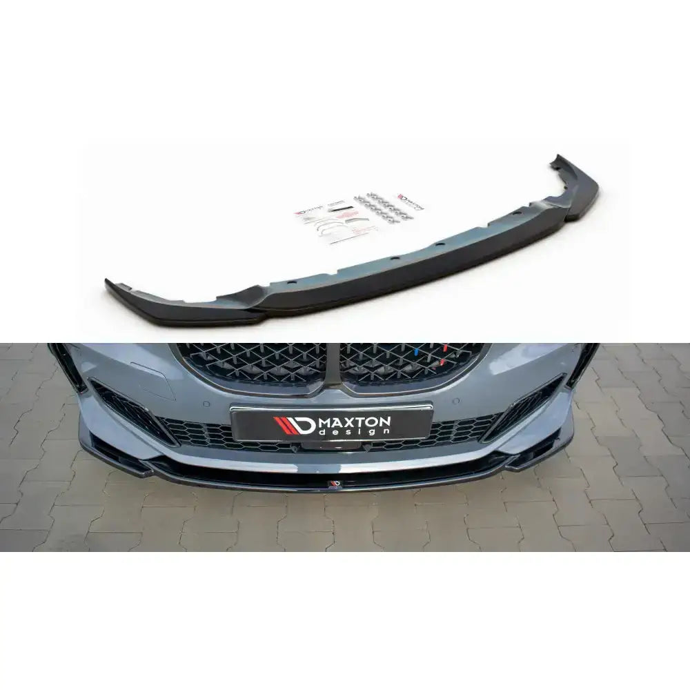 Frontleppe V.3 til BMW 1 F40 M-Pack i sort plast, vist montert foran på grå bil med utstyr ved siden av.