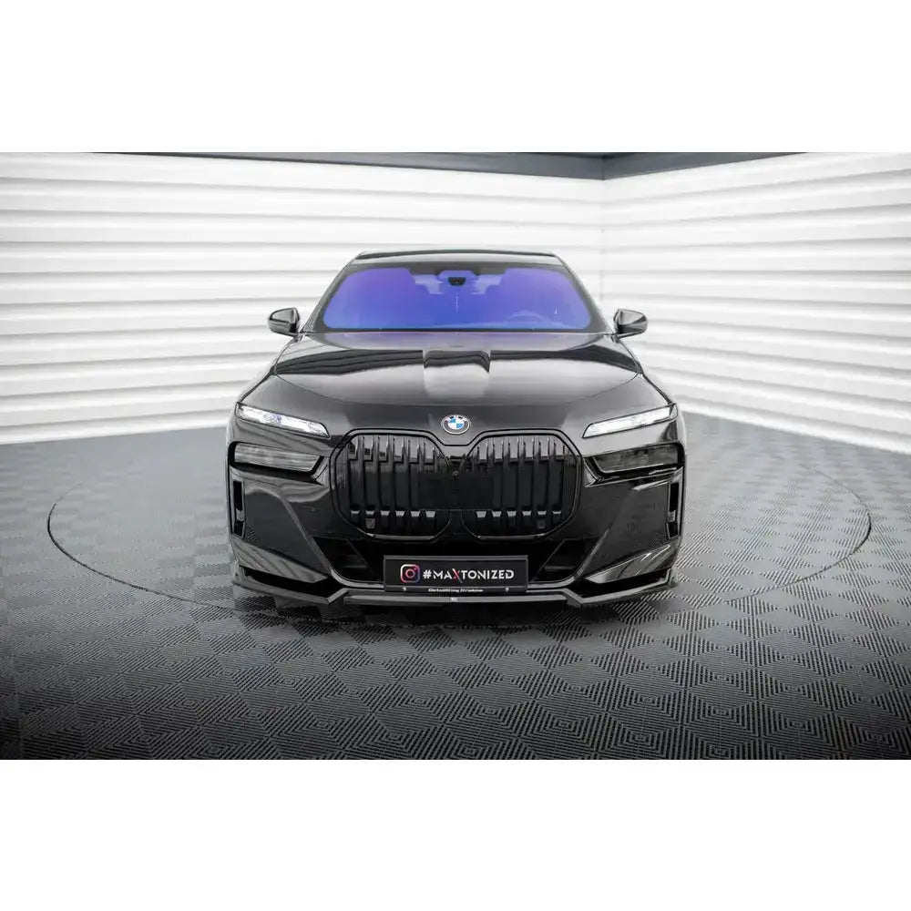 Frontspoiler på BMW 7 M-Pack G70 med svart grill og blåtonet frontrute innendørs.