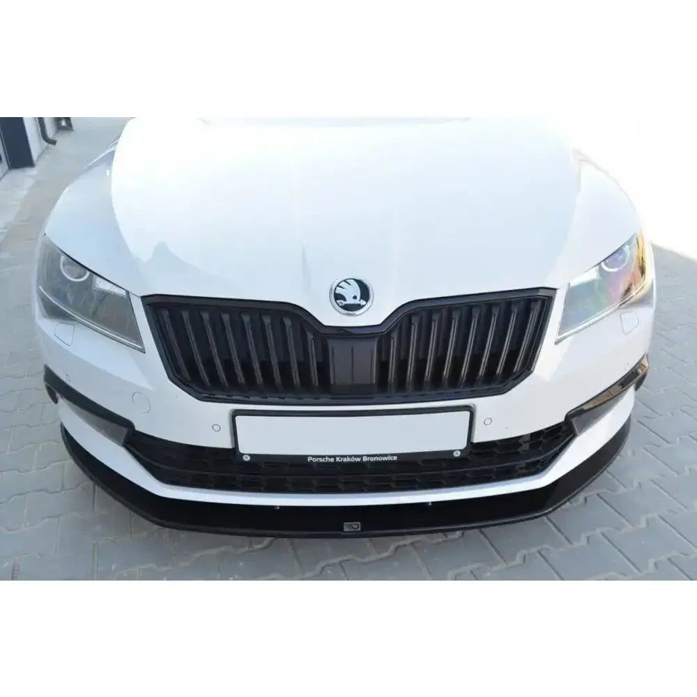 Front lip på Skoda Superb III V.3, hvit bil med sort grill og frontspoiler, sett rett forfra.