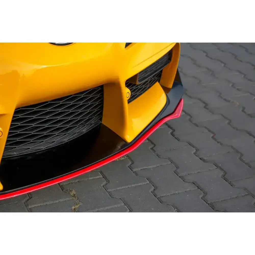 Frontspoiler til Toyota Supra Mk5 V.3 i sort og rød plast, montert på gul bil på grå belegningsstein.