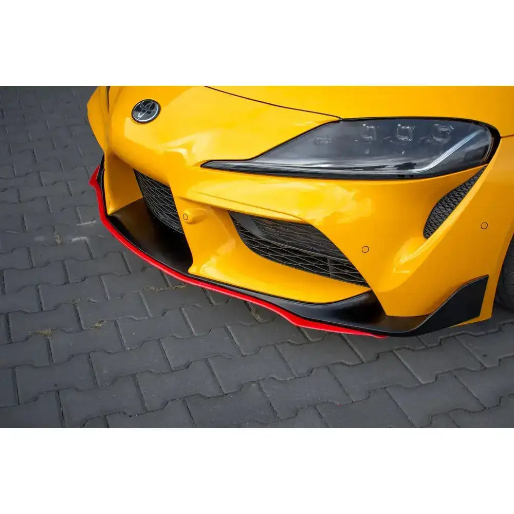 Front splitter til Toyota Supra Mk5, nærbilde av gul bil med sort og rød splitter på grå belegningsstein.