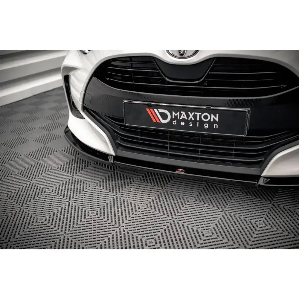 Frontsplitter til Toyota Yaris Mk4 V.3 i svart med luftinntak og Maxton design-skilt, sett forfra.