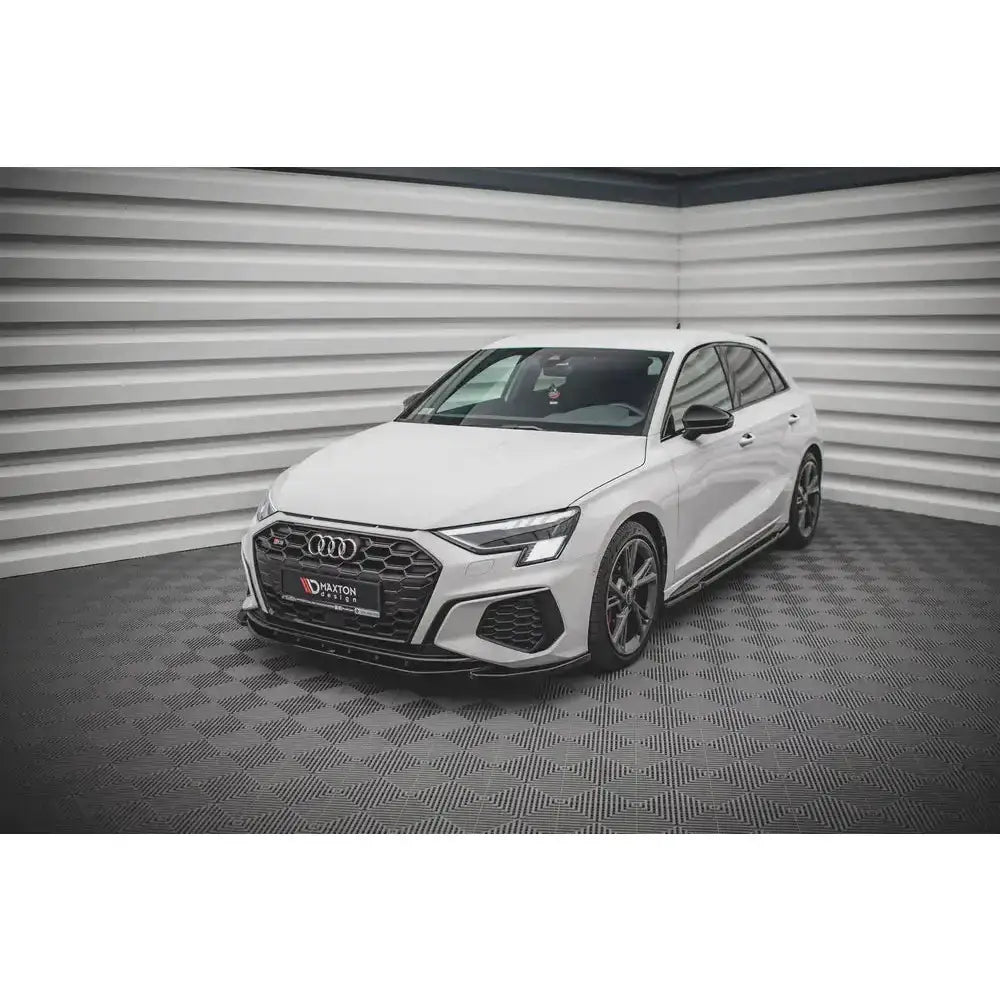Frontspoiler på hvit Audi S3 S-Line 8Y med sorte detaljer, sett skrått forfra innendørs.