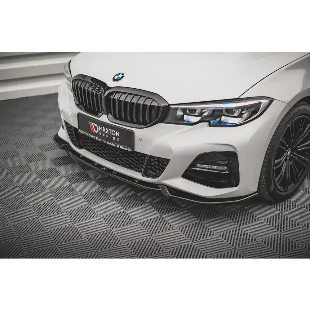 Frontsplitter på hvit BMW 3 G20/G21 M-Pack med sorte detaljer og mønstret gulv.
