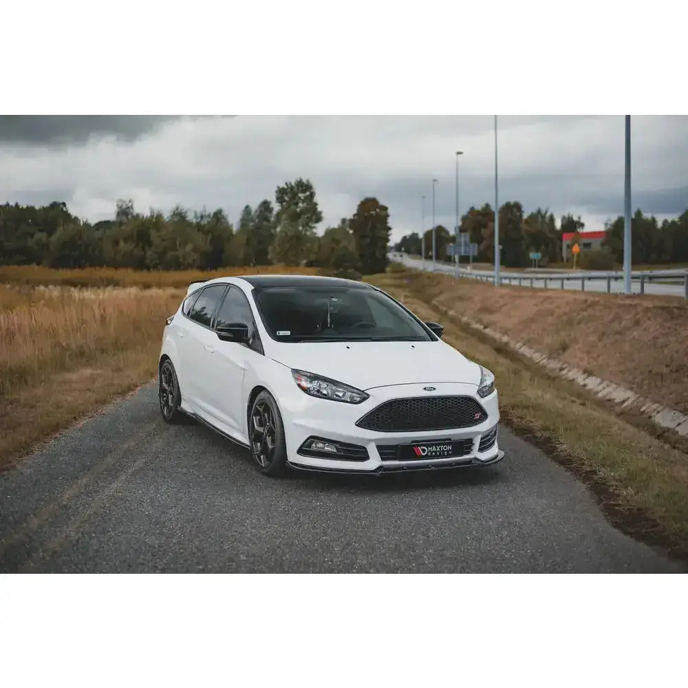 Frontspoiler på hvit Ford Focus ST Mk3 Facelift med sorte felger, sett i trekvart vinkel på landevei.