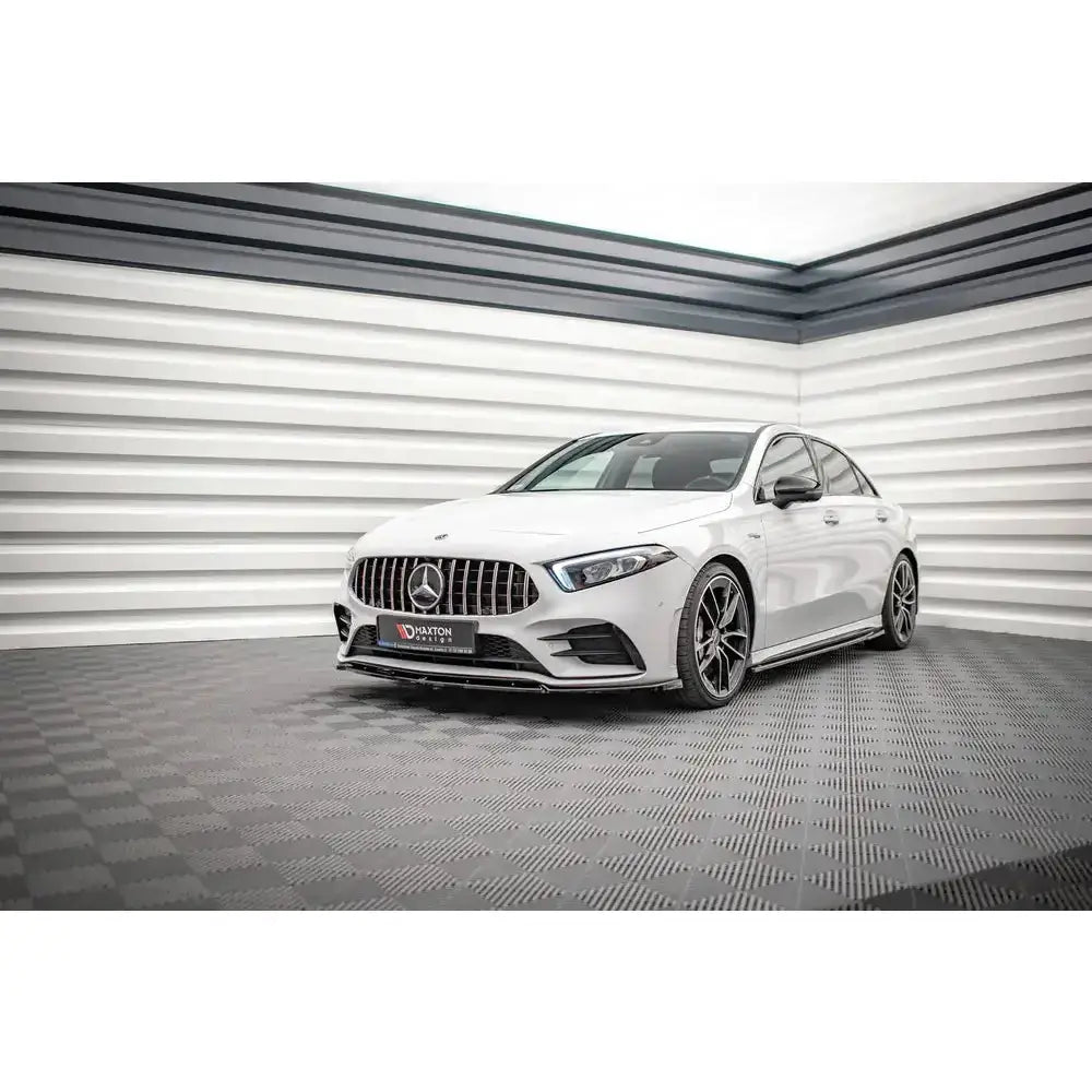Frontsplitter på hvit Mercedes A35 AMG W177 med sorte felger og sportslig grill, fotografert innendørs.