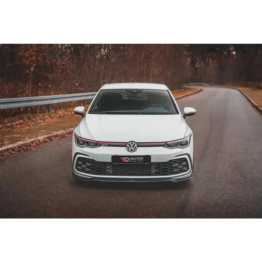 Frontspoiler på Volkswagen Golf 8 GTI V.4 med sorte og røde detaljer, fotografert utendørs.