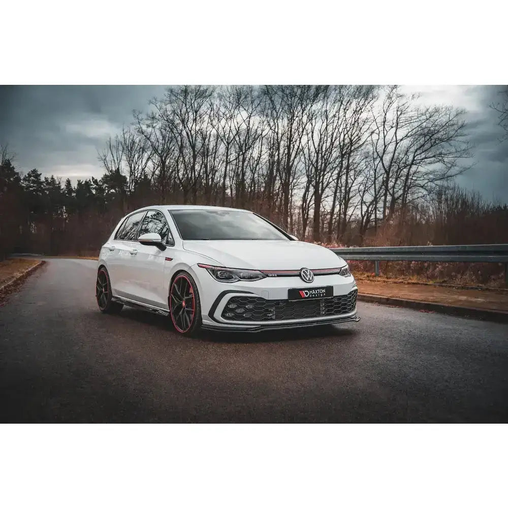 Front lip på Volkswagen Golf 8 GTI V.4, hvit bil med svarte detaljer og røde felgkanter utendørs.