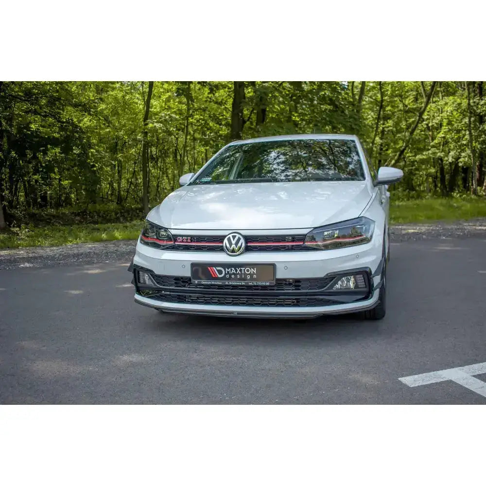 Front splitter på VW Polo GTI MK6 med svarte og røde detaljer, parkert foran grønn skog.