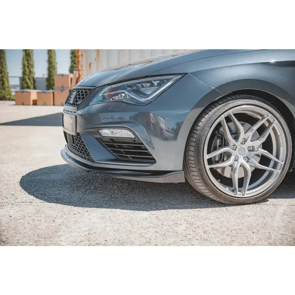 Front splitter på høyre side av grå Seat Leon Cupra med sølvfelg og lavprofildekk utendørs.