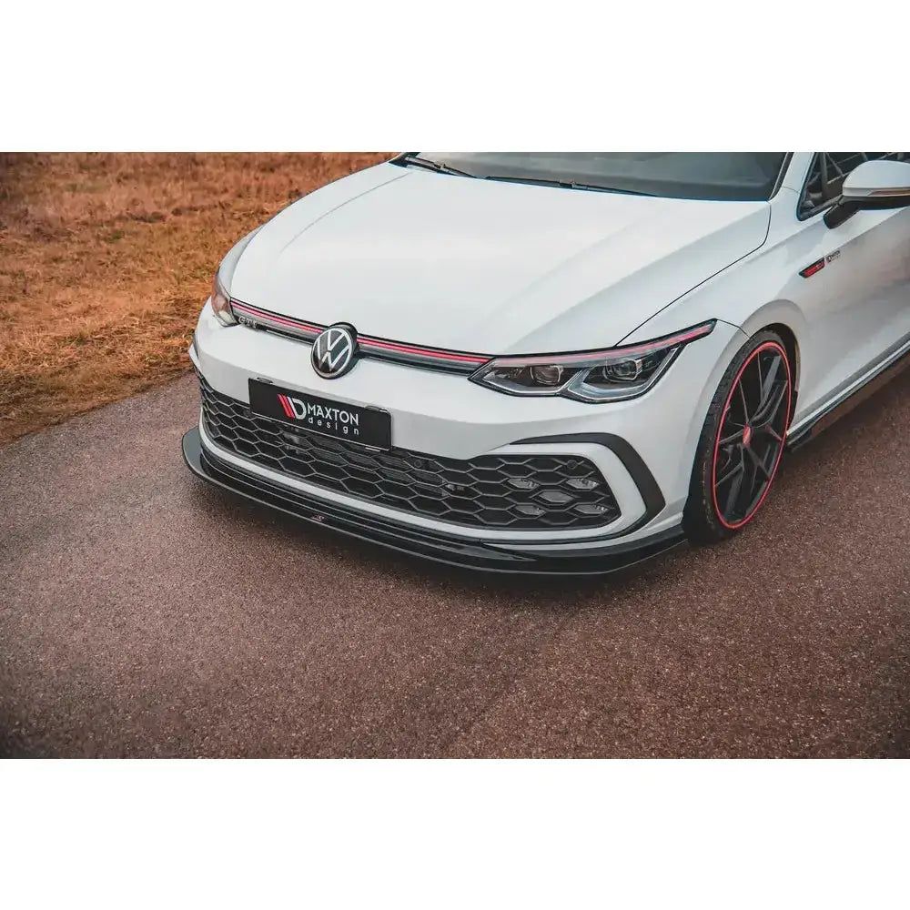 Frontsplitter på Volkswagen Golf 8 GTI V.5, nærbilde av hvit bil med røde detaljer og sporty styling.