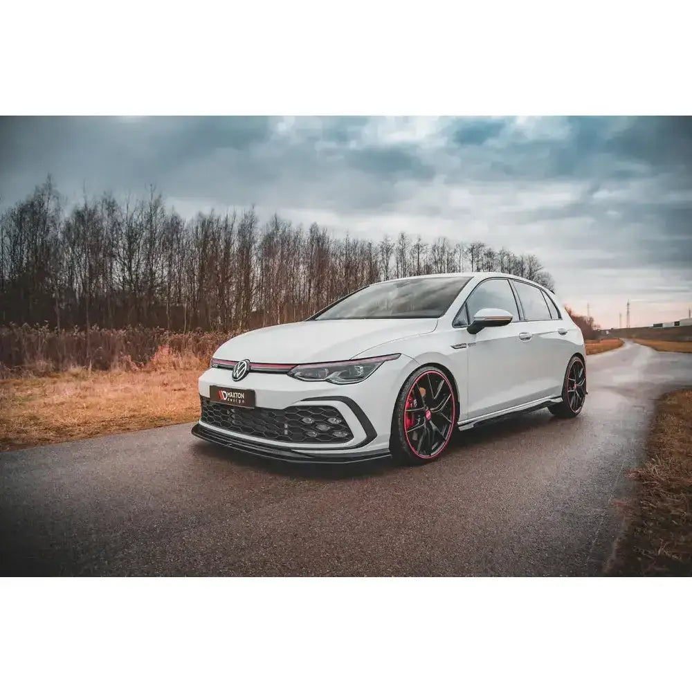 Front splitter på Volkswagen Golf 8 GTI med svarte detaljer og røde felgelementer på landevei.