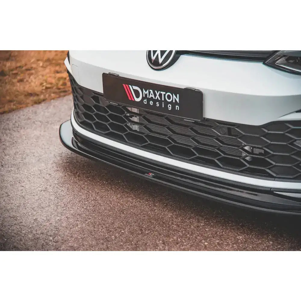 Frontleppe til Volkswagen Golf 8 GTI V.5 i blank sort plast sett forfra og nedenfra på hvit bil.