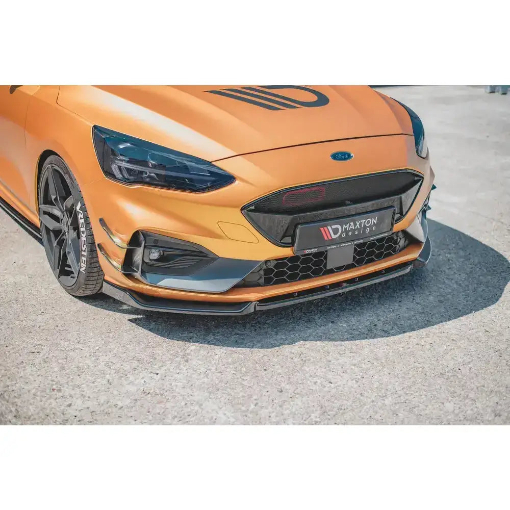 Frontsplitter på oransje Ford Focus ST med sorte detaljer og Maxton Design-logo på skiltet foran.
