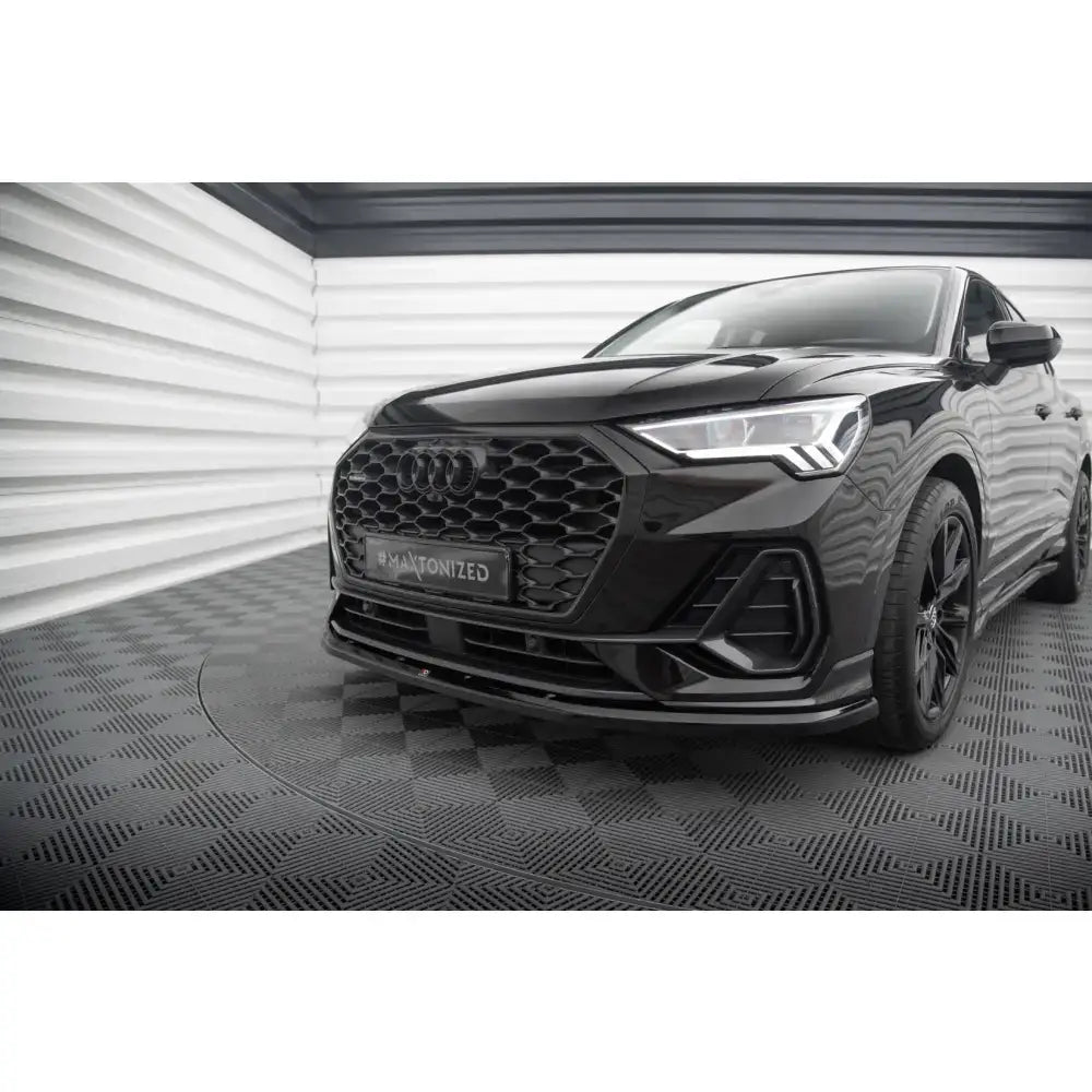 Front lip på Audi Q3 Sportback F3 med sort lakk, bikubemønstret grill og LED-frontlys i lyst rom.