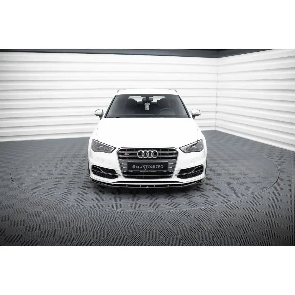 Frontsplitter på hvit Audi S3 med sort grill og kromdetaljer, fotografert forfra i lyst rom.