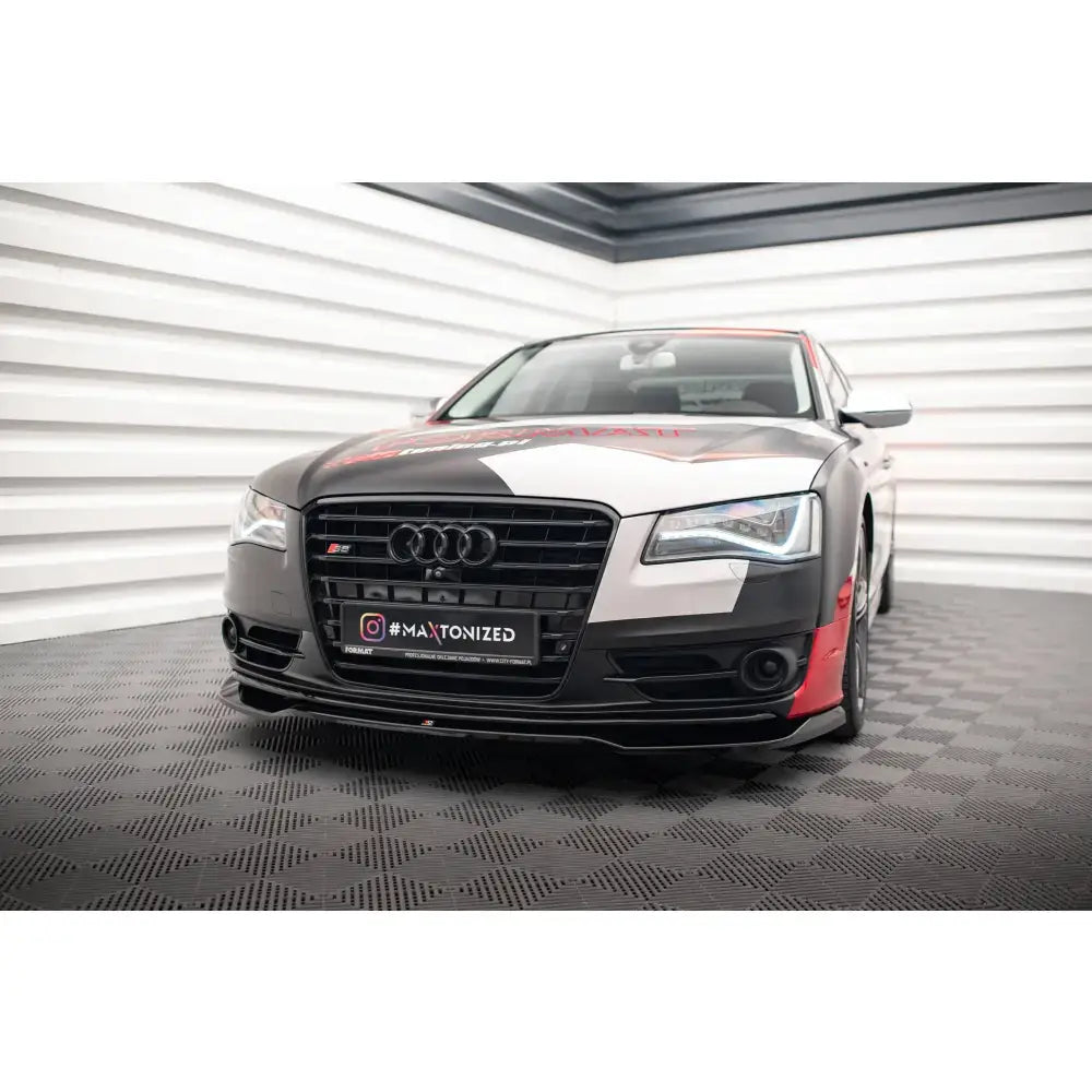 Frontspoiler på Audi S8 D4 med røde og hvite detaljer, sett forfra innendørs på mønstret gulv.