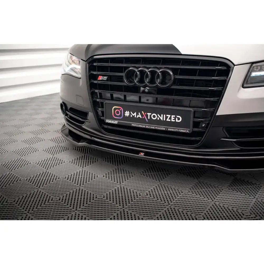 Front lip på Audi S8 D4 V1 frontleppe i blank svart under grillen, nærbilde mot mønstret gulv.