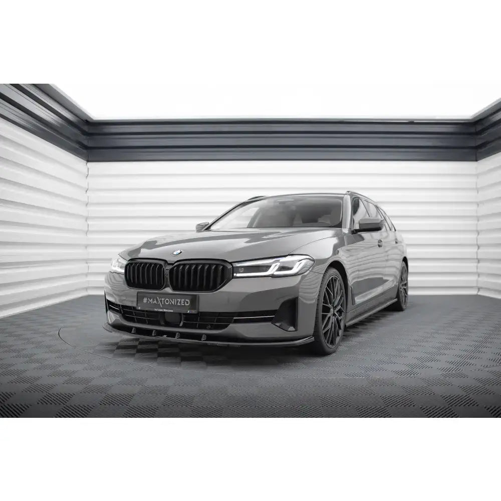 Frontspoiler på BMW 5 G30 Facelift med svarte felger, sett forfra i lyst innendørs rom.