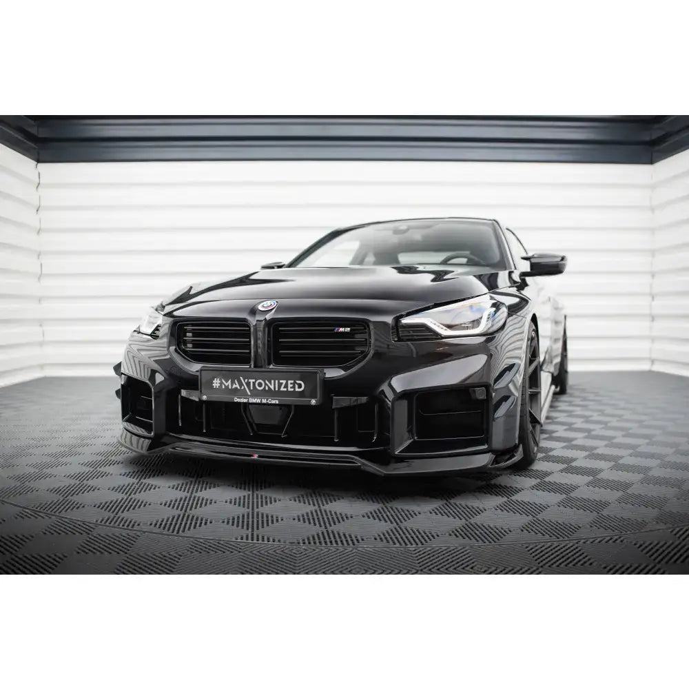 Frontspoiler V1 til BMW M2 G87 montert på sort sportsbil med markante luftinntak.