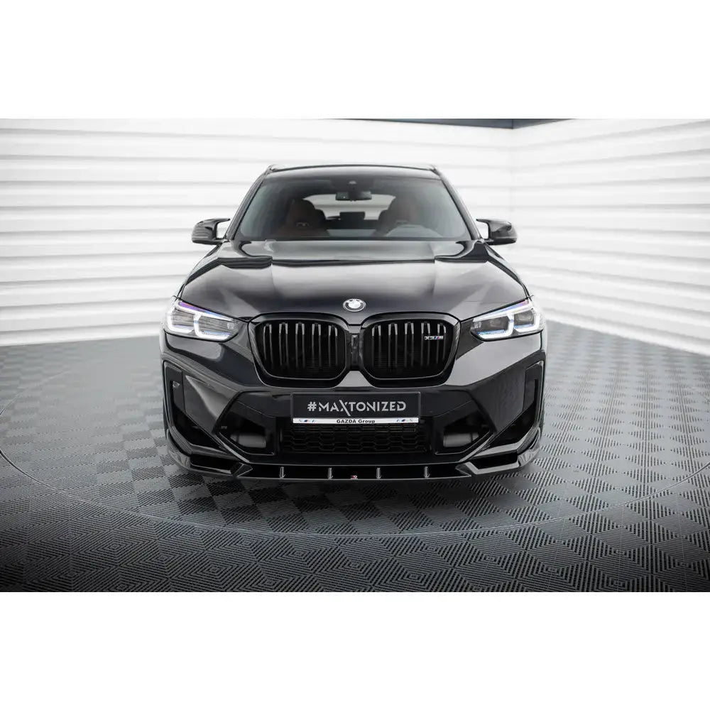 Frontsplitter på BMW X3 M F97 Facelift sett forfra med markant grill i lyst rom med rutet gulv.