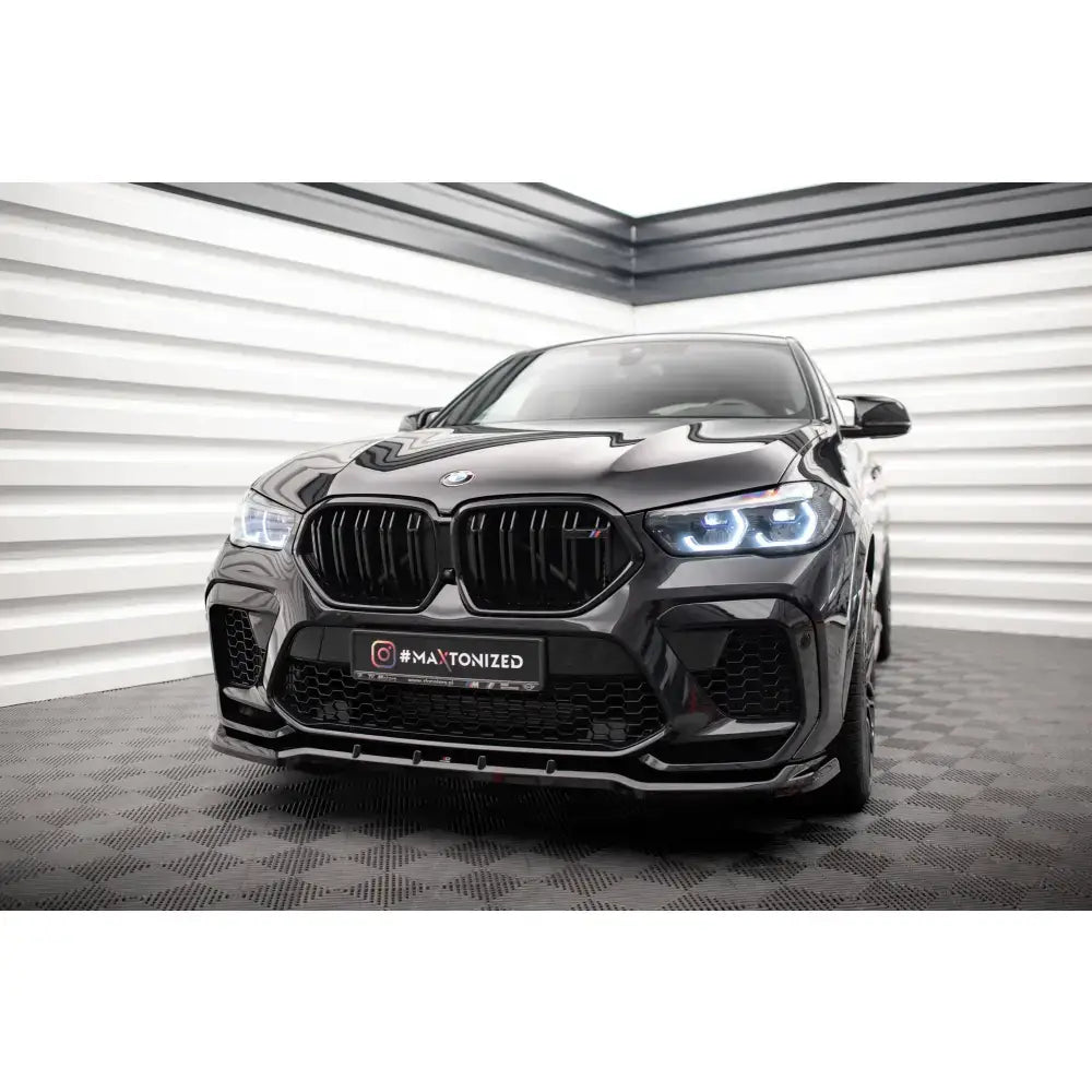 Frontspoiler V1 BMW X6 M F96 på sort bil med markante LED-frontlykter og stor sort grill.