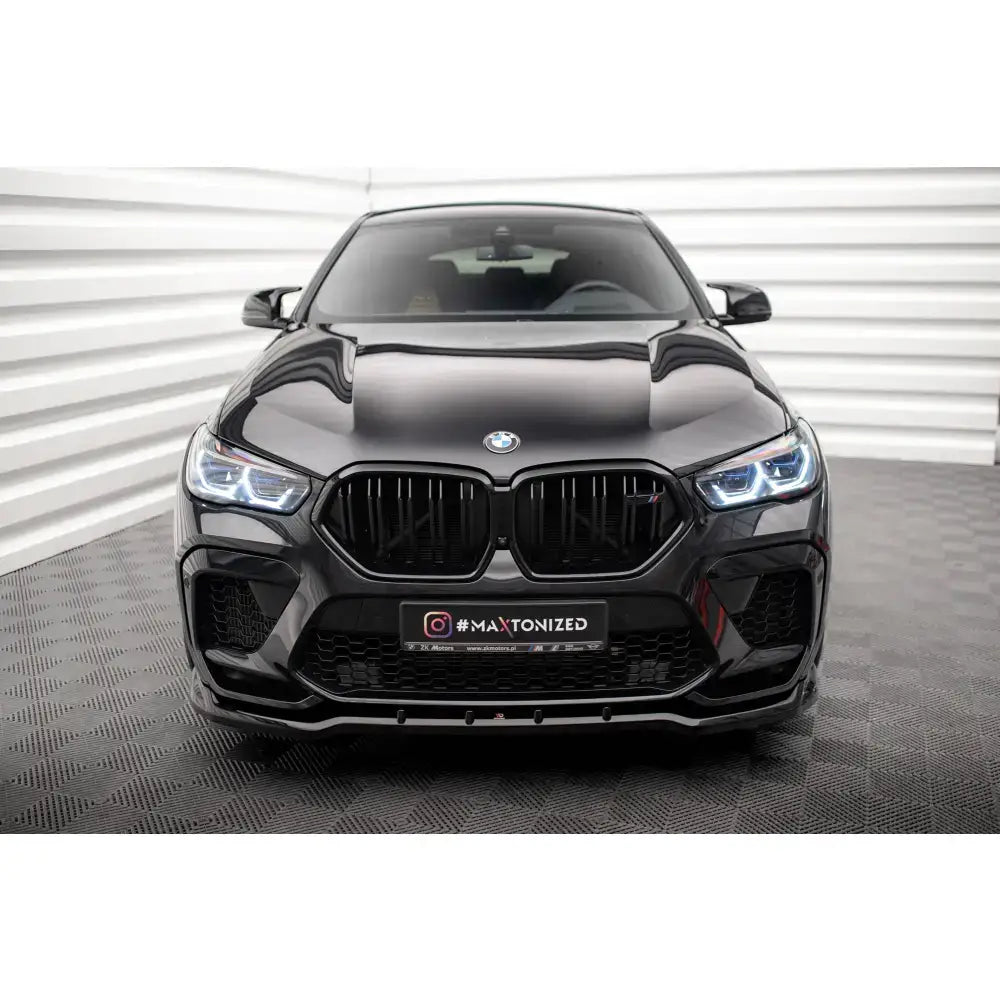 Frontsplitter på BMW X6 M F96, sort bil rett forfra med LED-frontlykter og sporty støtfanger.
