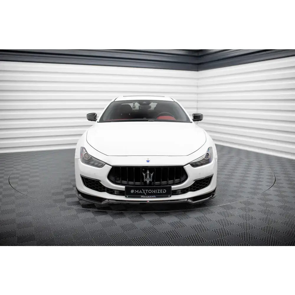 Frontsplitter på Maserati Ghibli Mk3 Facelift, hvit bil sett forfra med svart grill og røde seter.