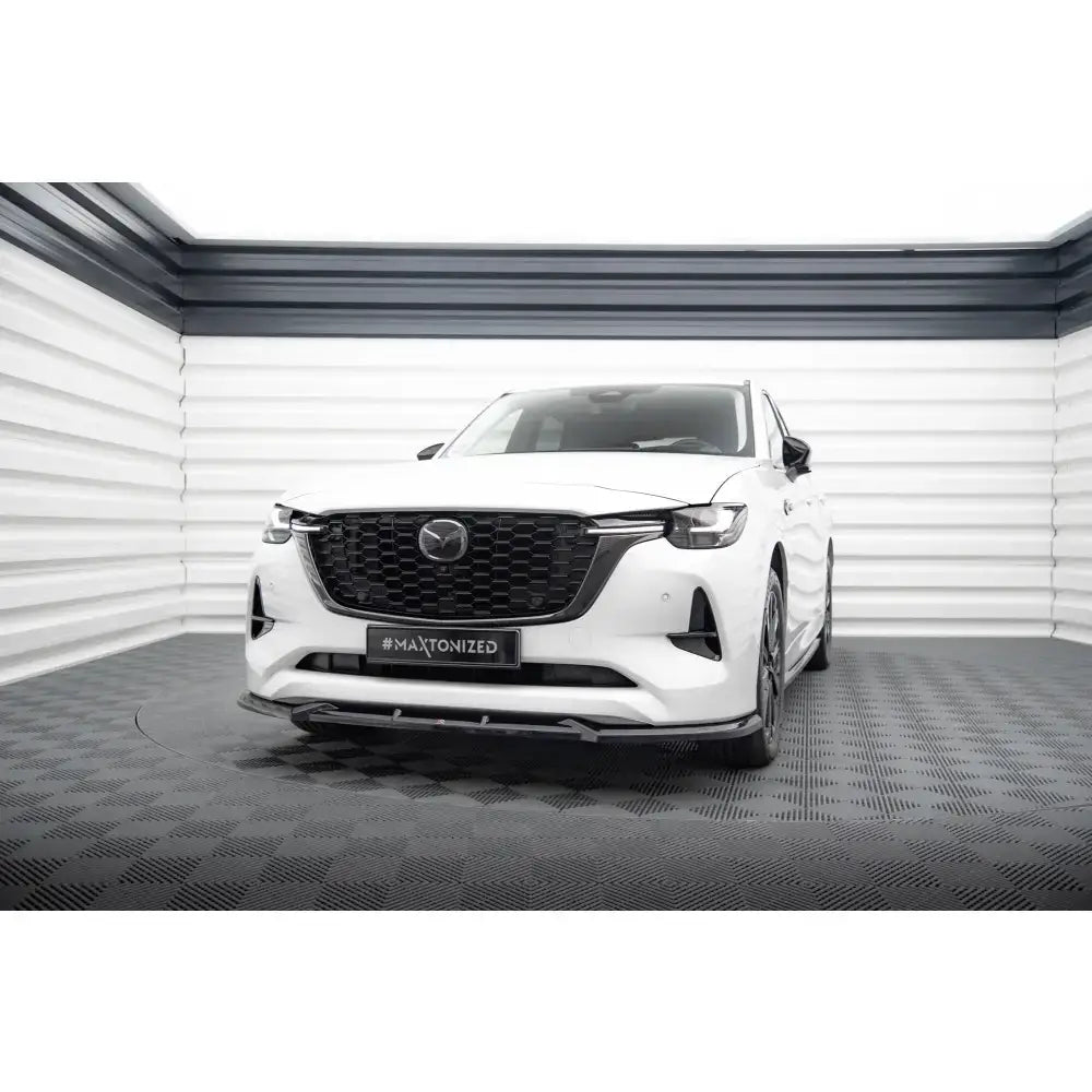 Frontspoiler på Mazda CX-60 Mk1 hvit SUV med sort grill, avbildet forfra i lyst rom på sort gulv.