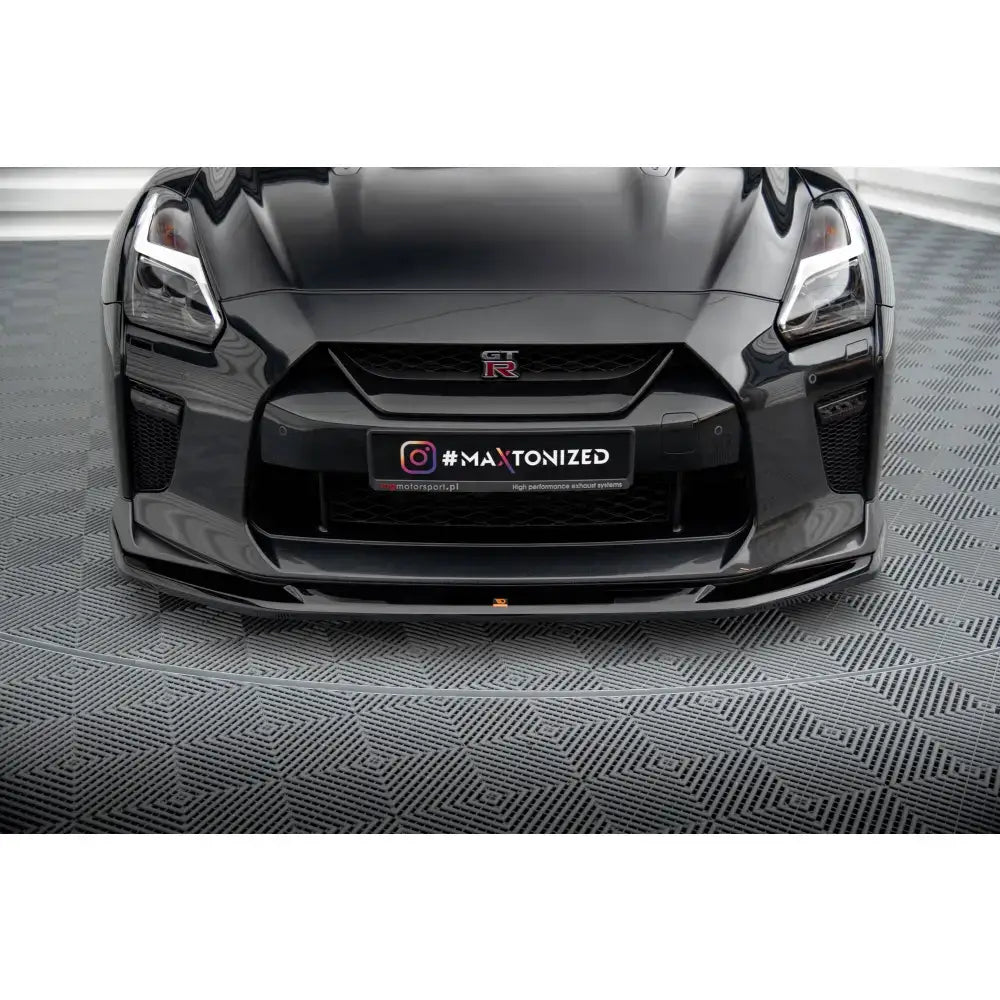 Front lip på sort Nissan GTR R35 Facelift, sett forfra, med blank finish og markerte linjer.
