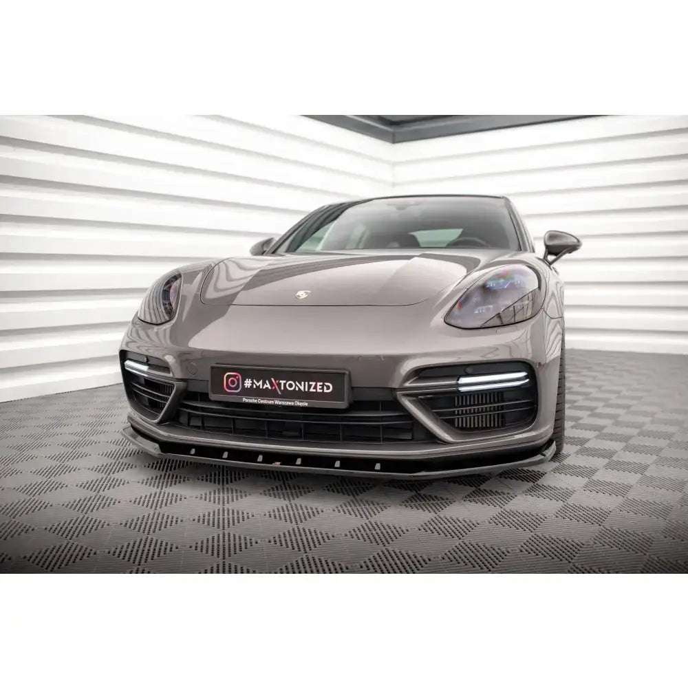 Frontsplitter på Porsche Panamera E-Hybrid 971 sett fra lav frontvinkel i lyst rom med mønstret gulv.