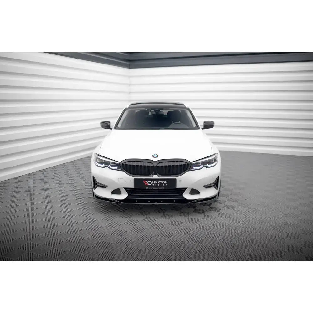 Frontspoiler til BMW 3 Sport Line G20/G21, sort detalj på hvit bil sett forfra i lyst industrilokale.