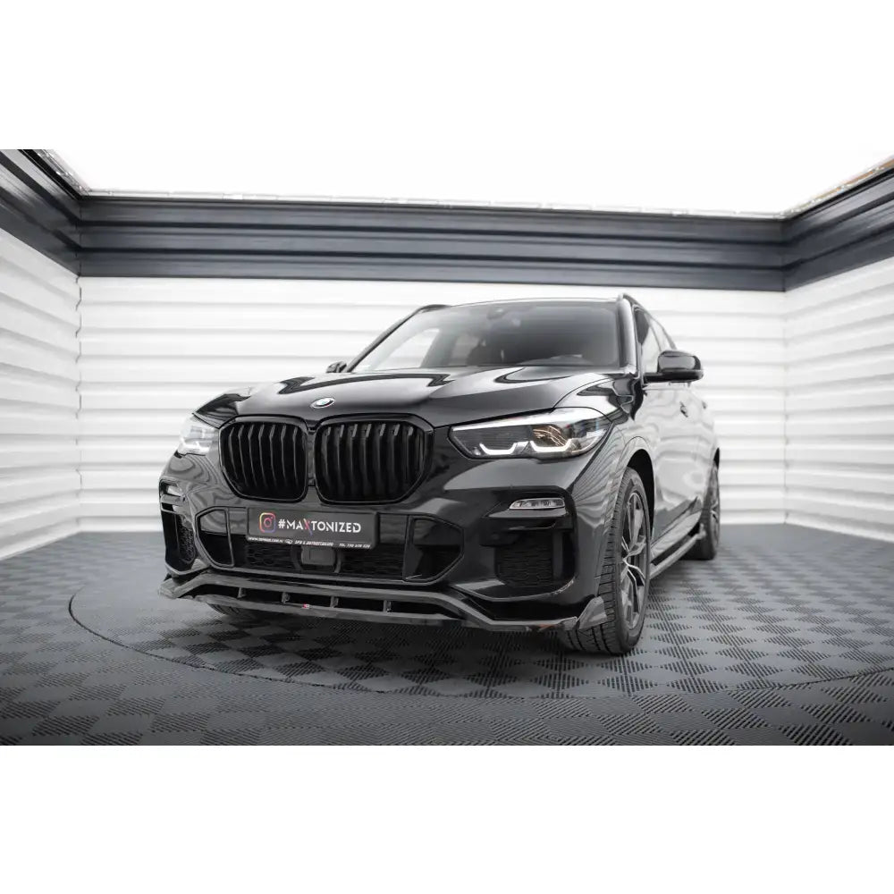 Frontspoiler på BMW X5 M-Pack G05, svart SUV sett skrått forfra med markant grill og frontlykter.