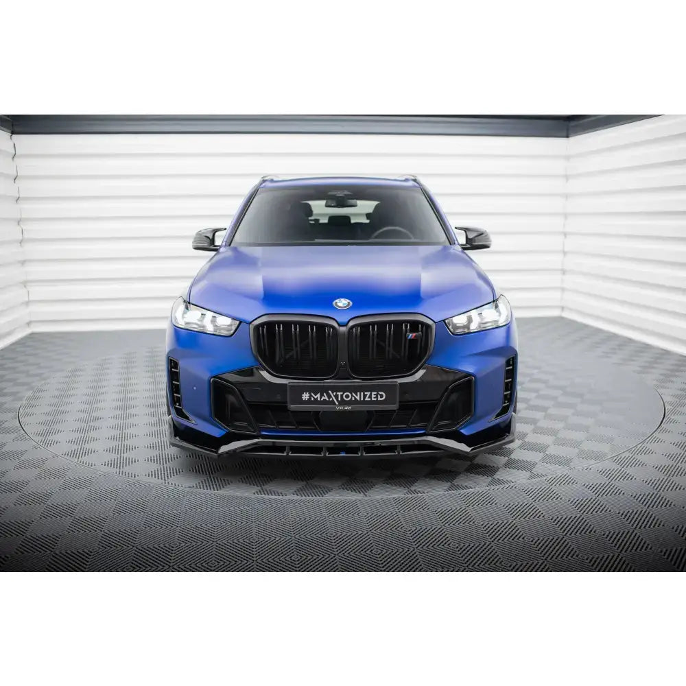 Frontspoiler på blå BMW X5 M-Pack G05 Facelift sett forfra med svart grill i lyst rom.
